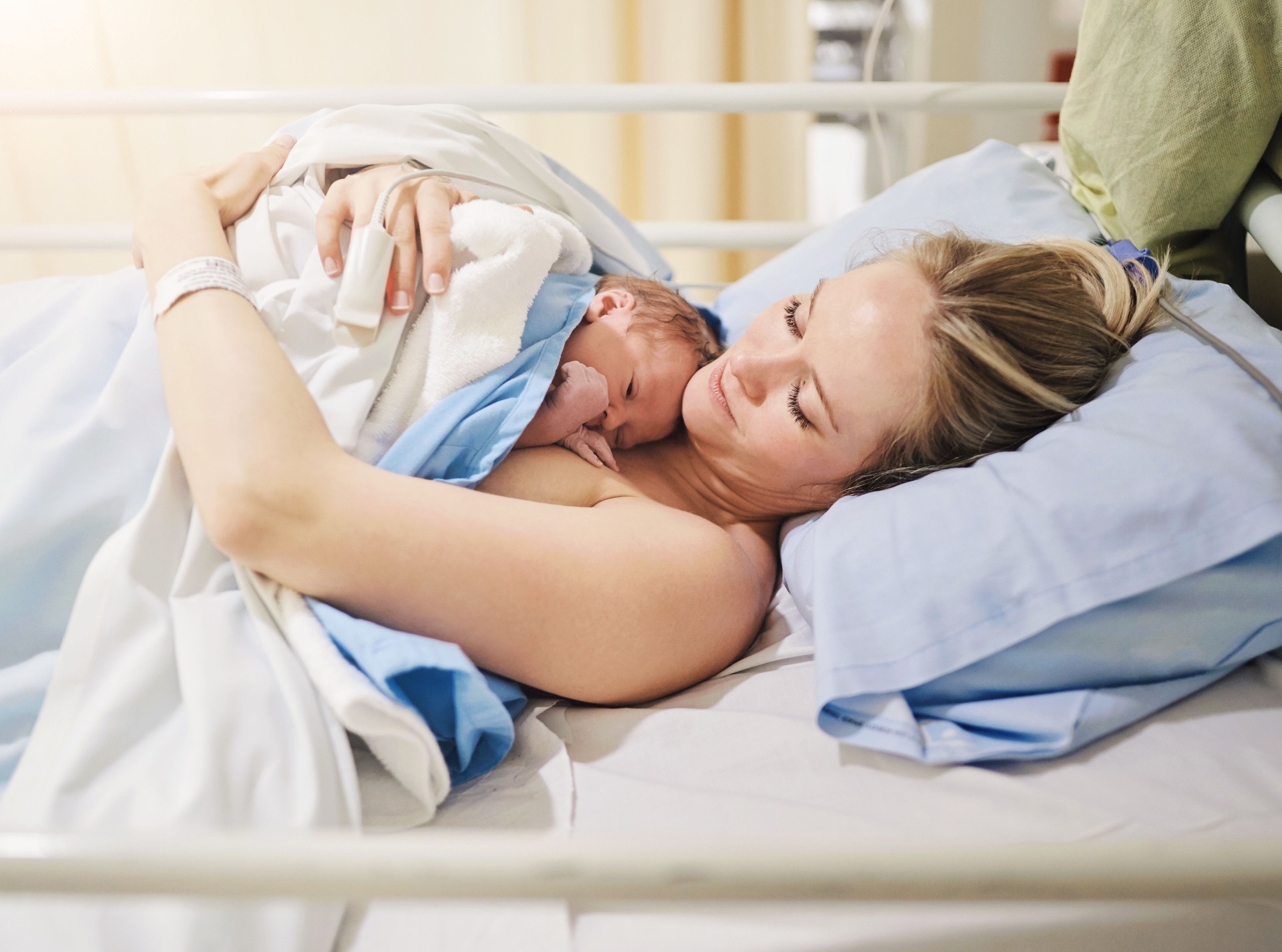 Birth, love or skin with mother and baby in hospital for healthcare, maternal security or medical. Bed, family and safety with woman hugging newborn infant in maternity ward of clinic for warmth